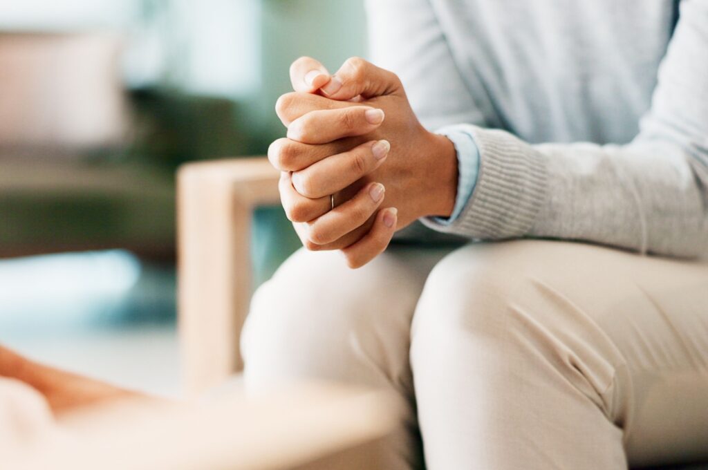 A woman sitting with her hands clasped.